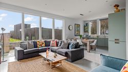 Modern open-plan living room and kitchen with large windows and colorful furniture