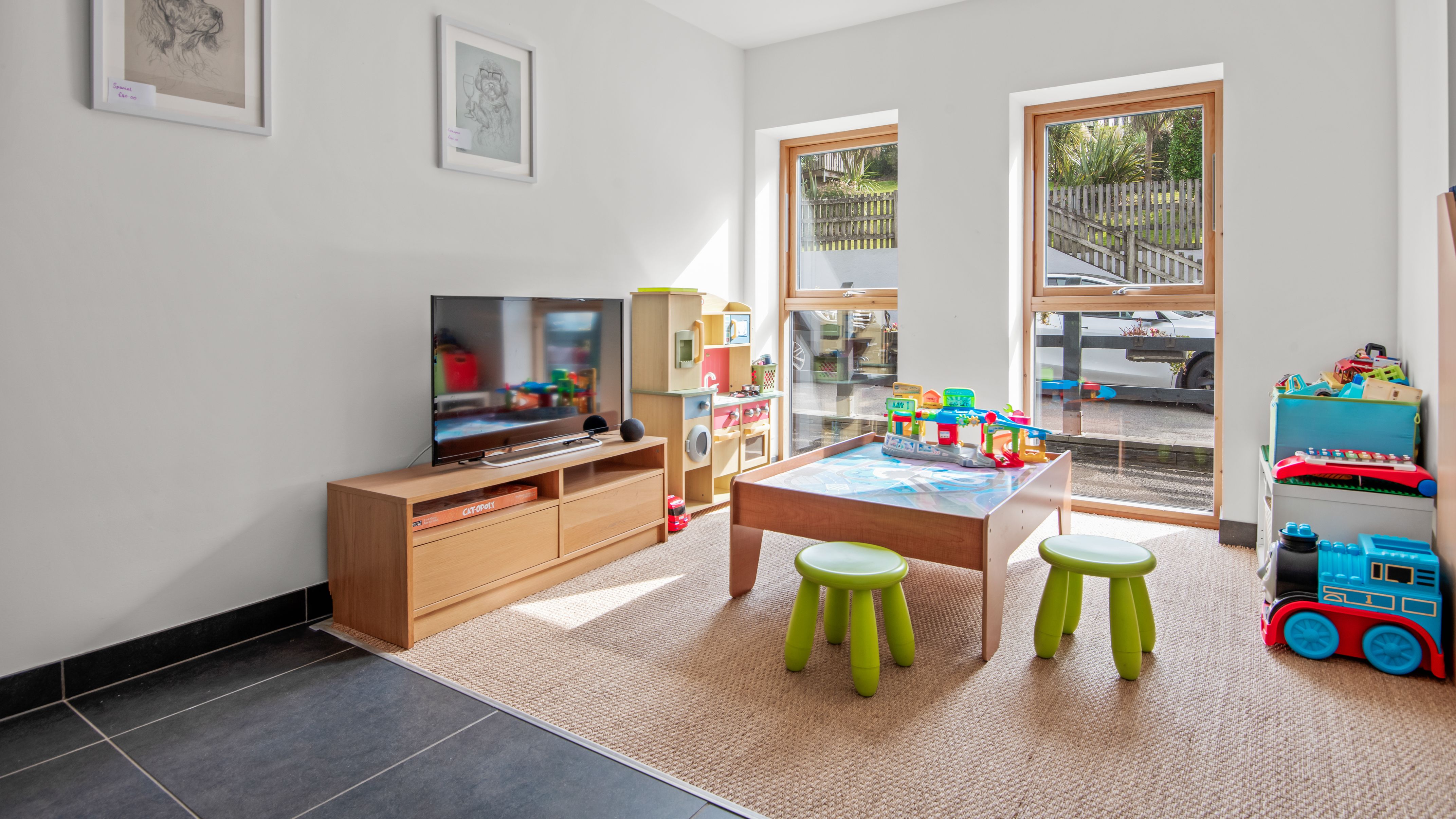 Bright playroom with wooden furniture, children's toys, and a TV.