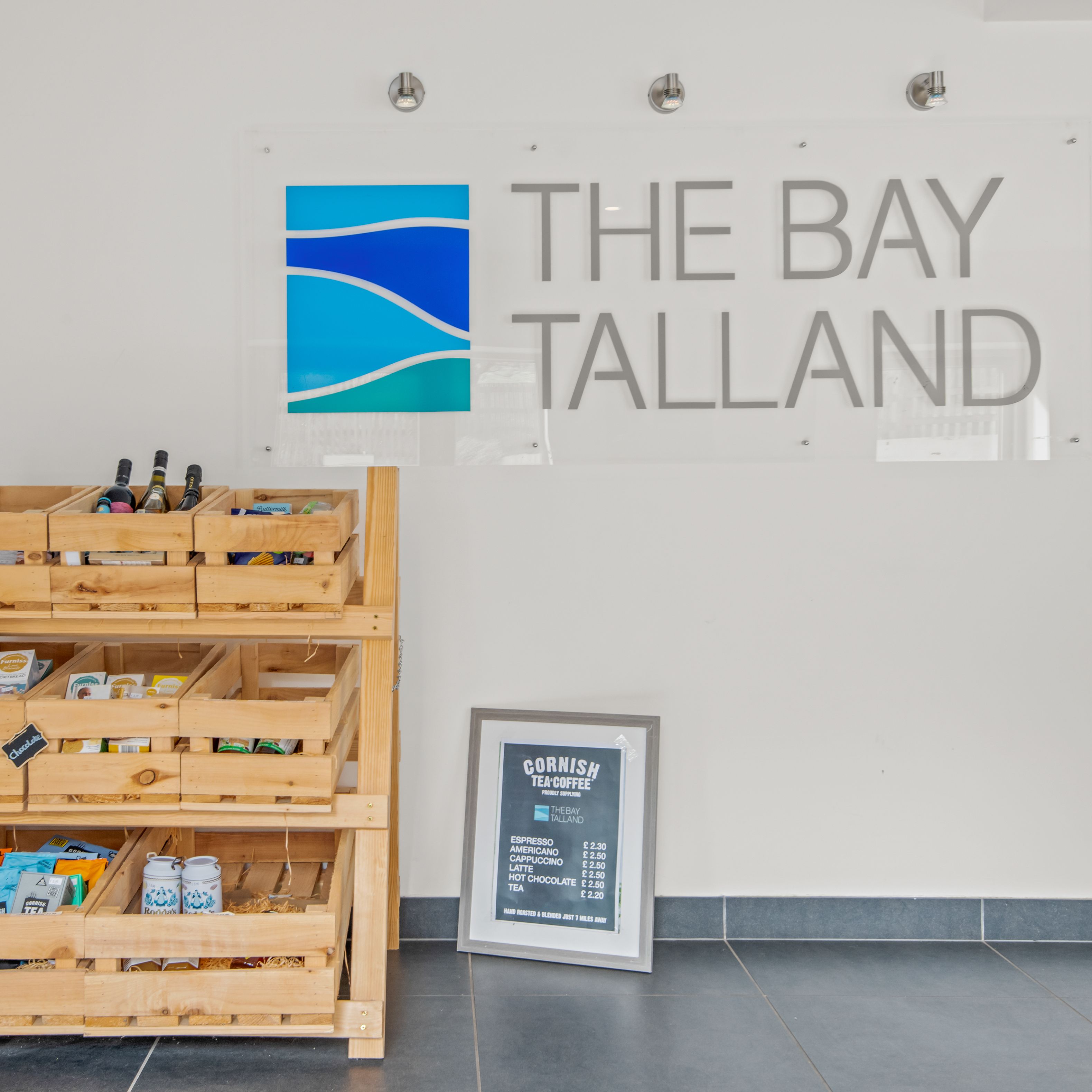 Wooden display racks with snacks and beverages at The Bay Talland reception area