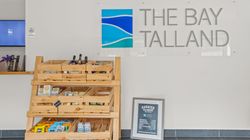 Wooden display racks with snacks and beverages at The Bay Talland reception area