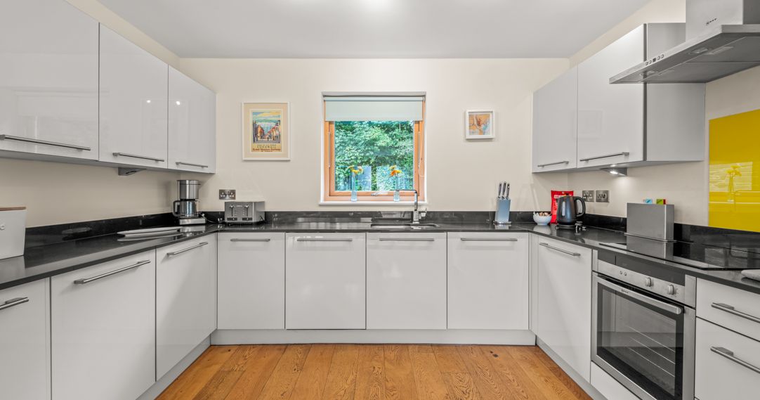Modern kitchen with white cabinets, black countertops, and wooden flooring