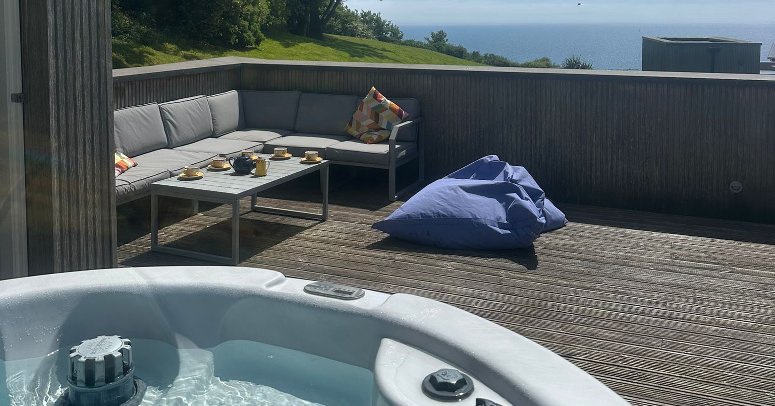 Outdoor deck with a hot tub, seating area, and ocean view