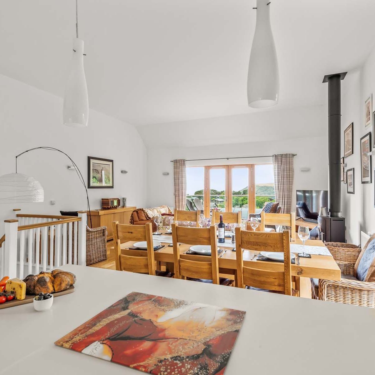 Bright and modern dining and living room with wooden furniture and large windows overlooking a scenic view.