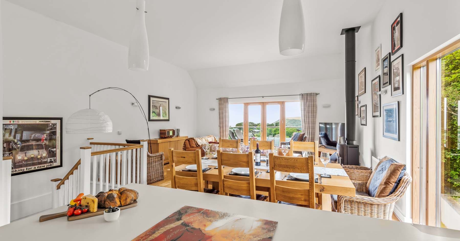 Bright and modern dining and living room with wooden furniture and large windows overlooking a scenic view.