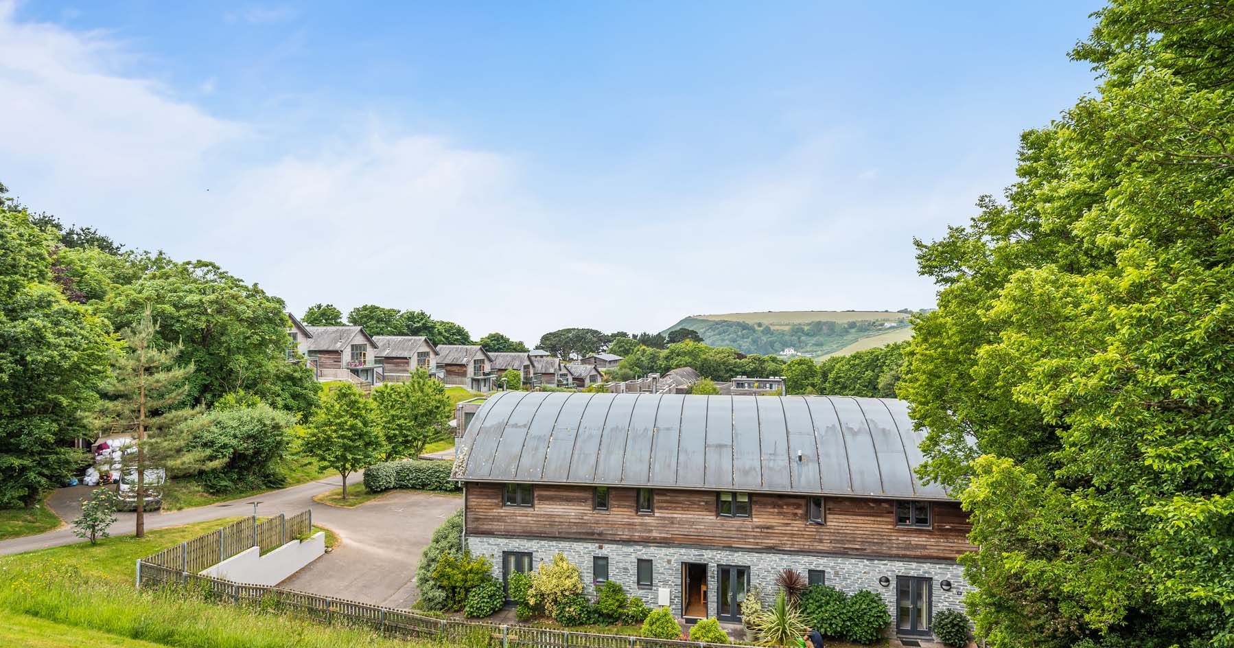 Modern residential buildings with wooden and stone exteriors surrounded by greenery on a sunny day