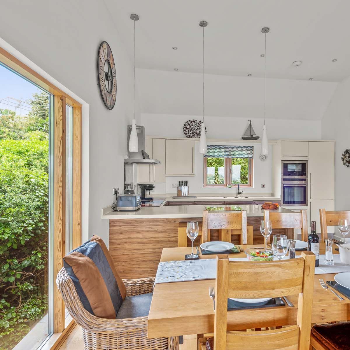 Modern kitchen and dining area with wooden table and chairs set for a meal