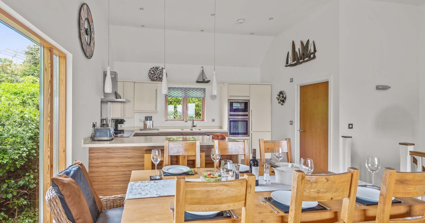 Modern kitchen and dining area with wooden table and chairs set for a meal