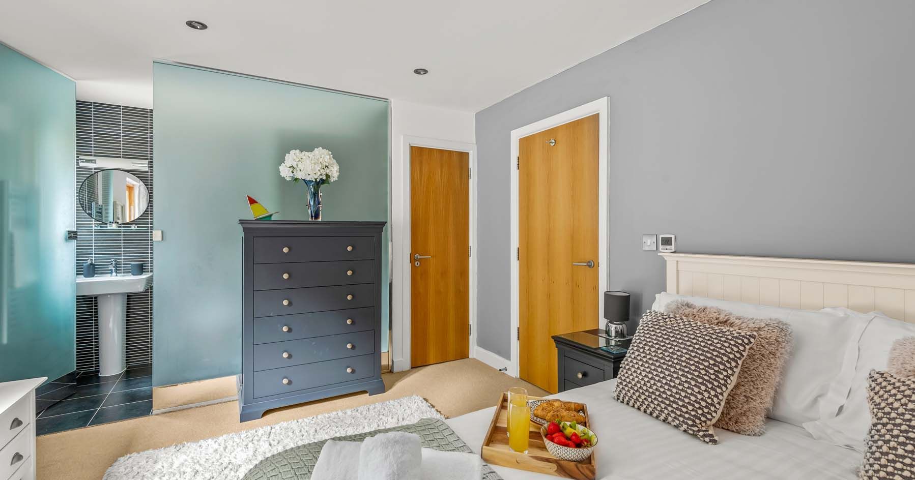 Modern bedroom with grey walls, double bed, and en-suite bathroom