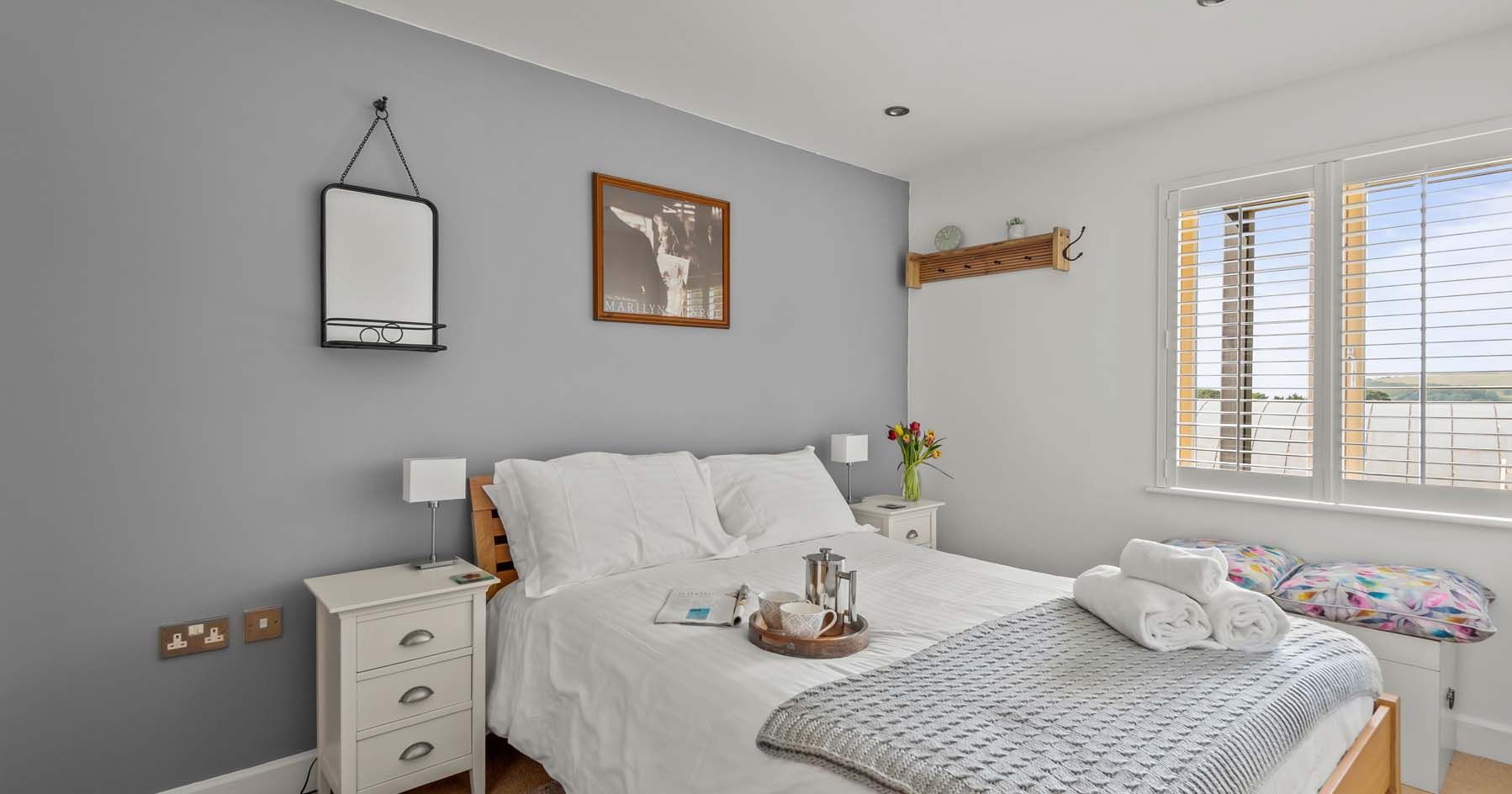 Modern bedroom with a double bed, grey accent wall, and white bedding.