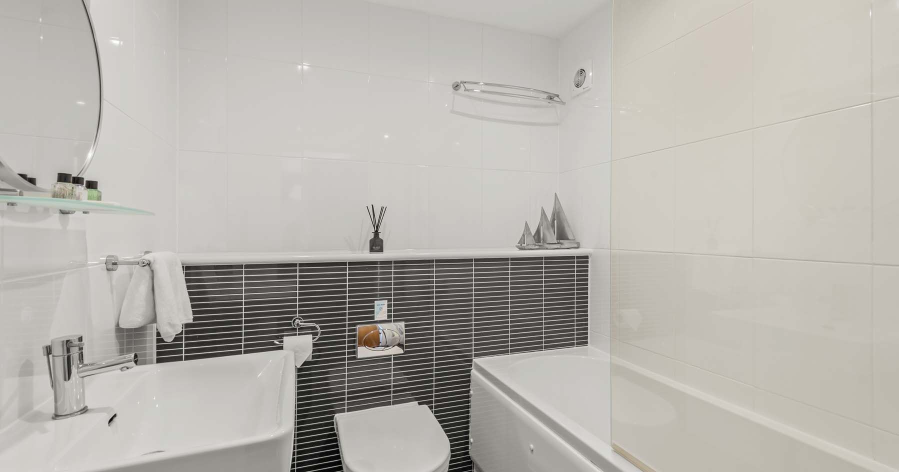 Modern white and black tiled bathroom with sink, toilet, and bathtub