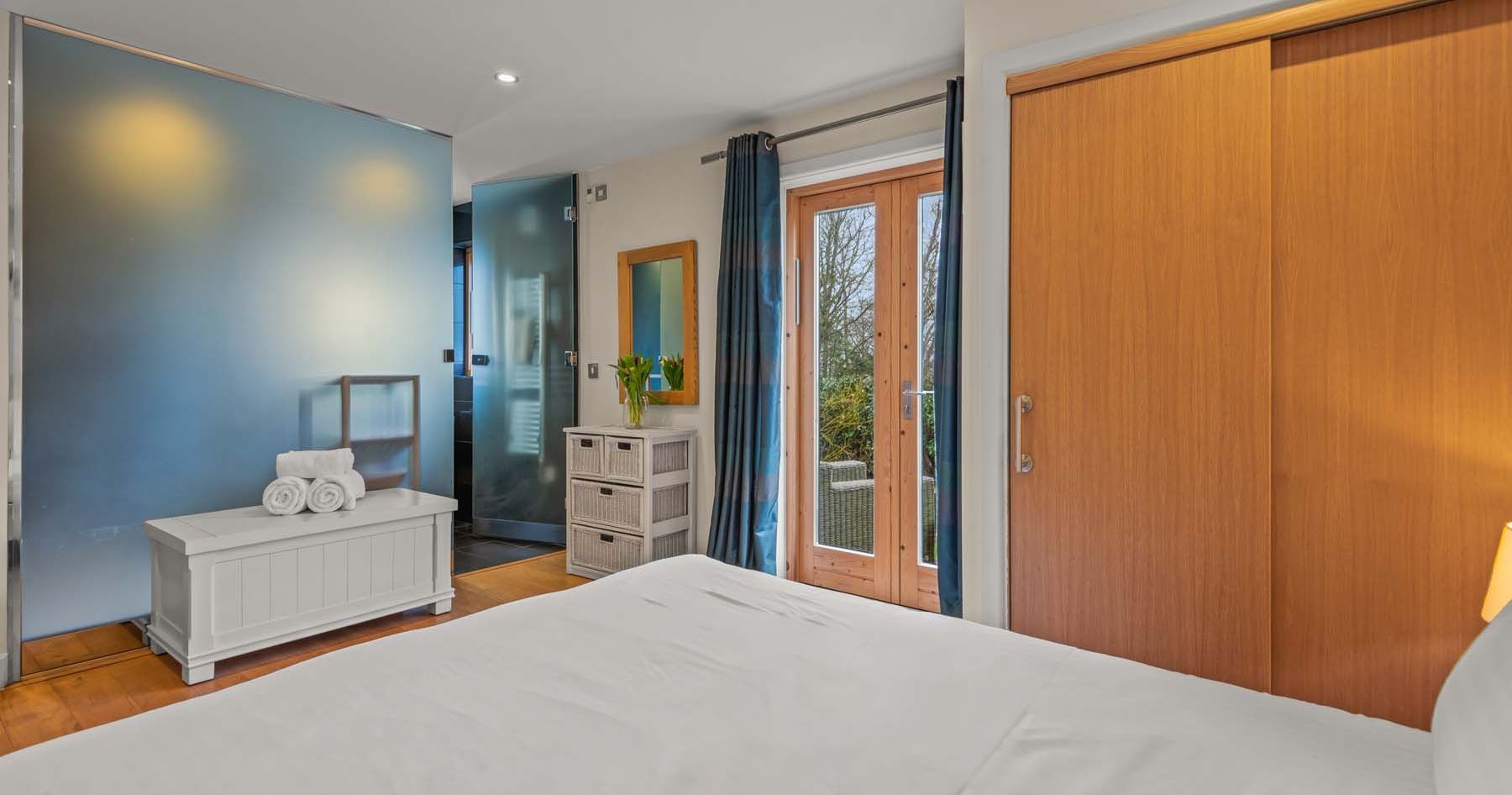 Modern bedroom with frosted glass wall, double doors, and wooden accents
