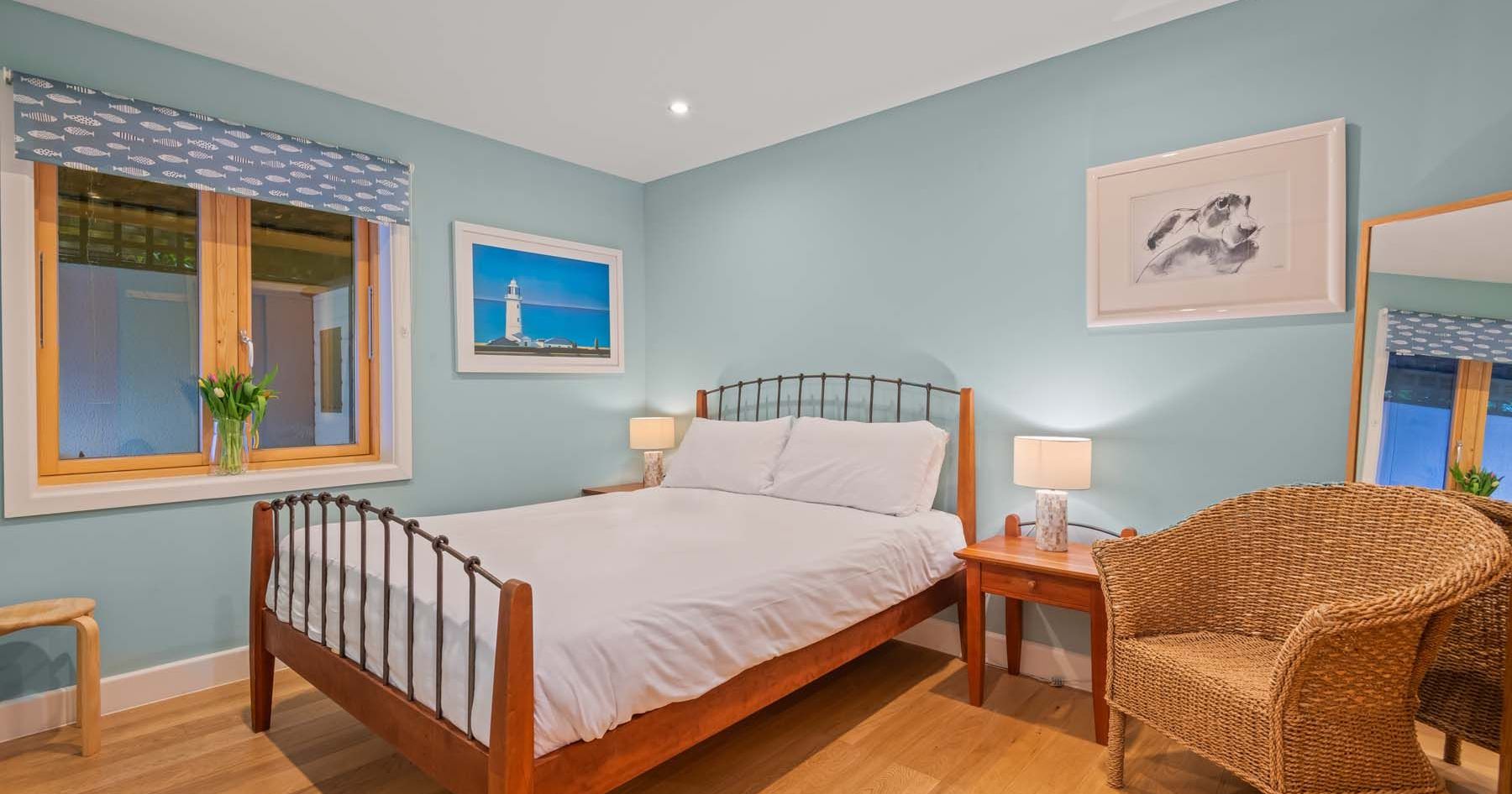 Cozy bedroom with blue walls, wooden furniture, and wicker chair