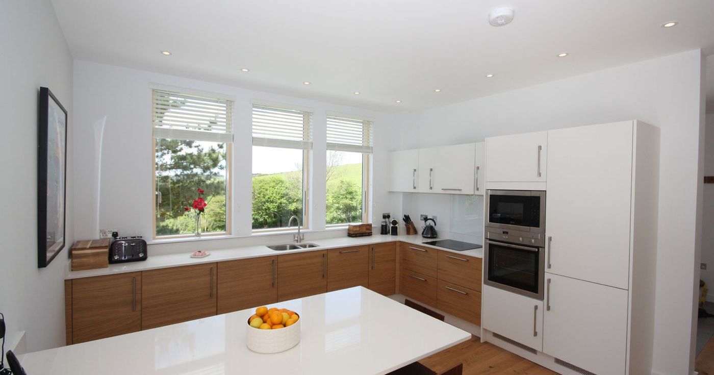 Modern kitchen with white countertops, wood cabinets, and large windows