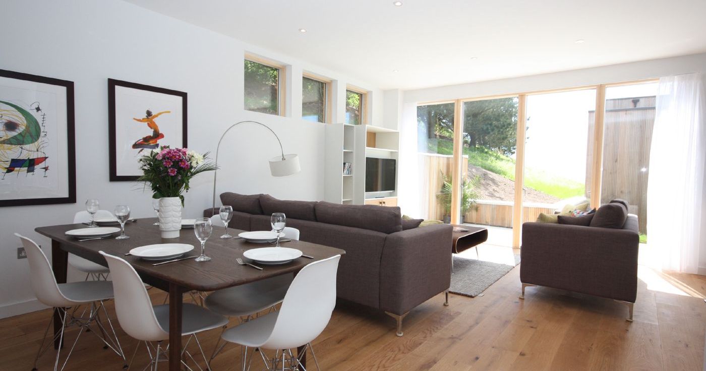 Modern open-plan living and dining room with large windows and stylish furniture