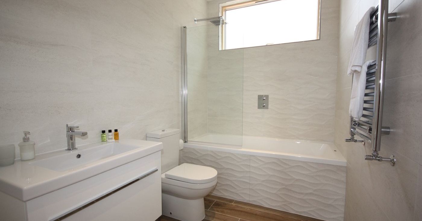 Modern bathroom with white fixtures and wood-look floor