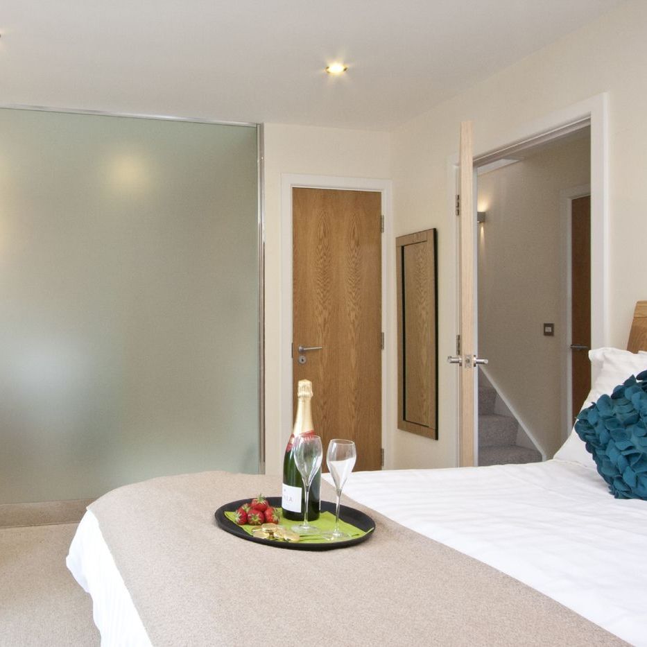 Modern bedroom with ensuite bathroom, champagne, and strawberries on bed