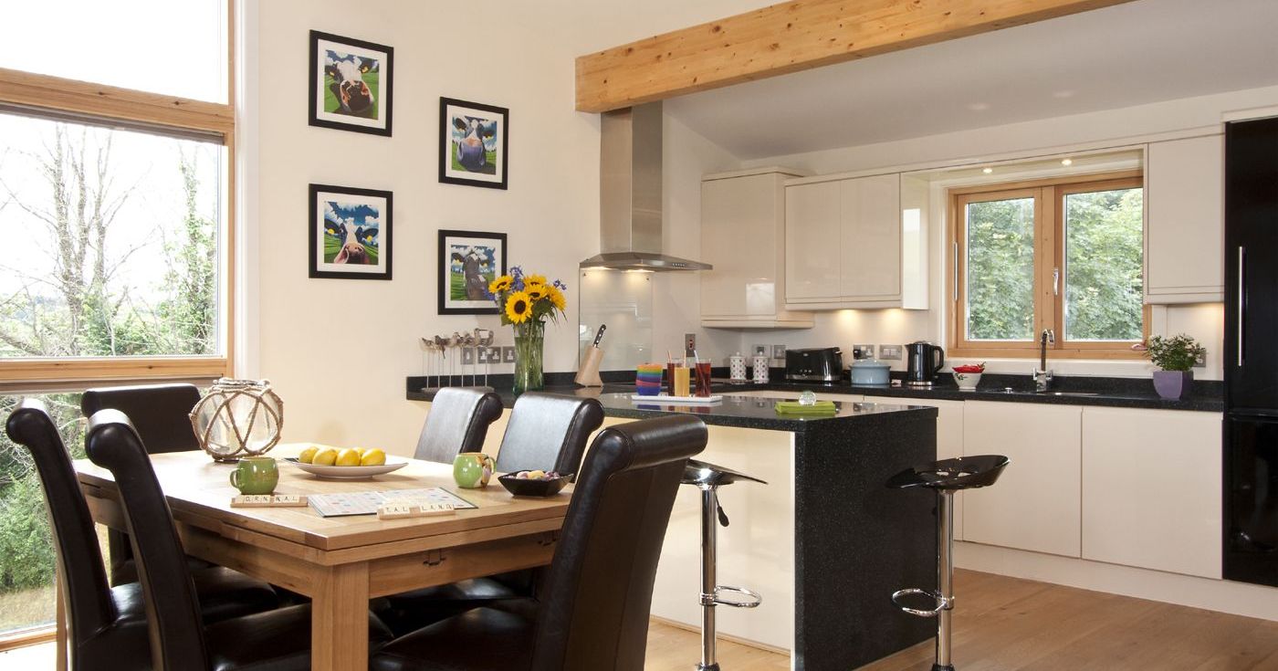 Modern kitchen and dining area with wooden dining table, leather chairs, and white cabinets.