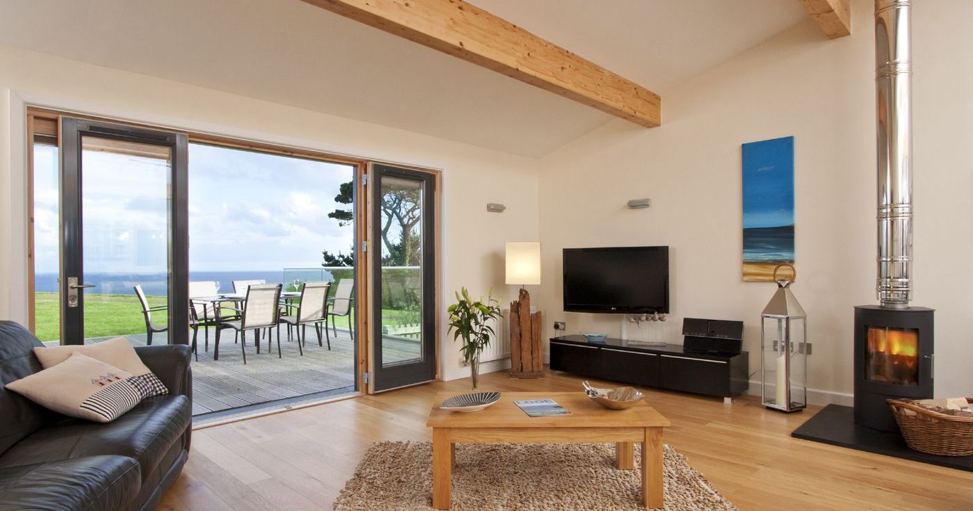 Modern living room with large glass doors opening to an outdoor dining area and ocean view