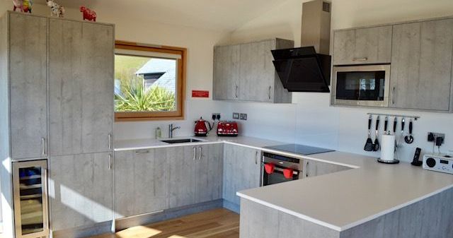 Modern kitchen with grey cabinets, white countertops, and stainless steel appliances.