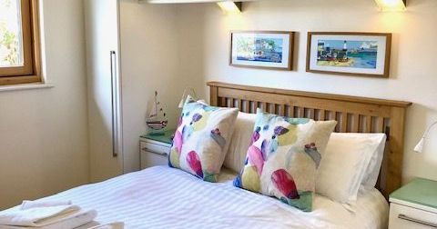 Bright bedroom with double bed, colorful pillows, and wall cabinets