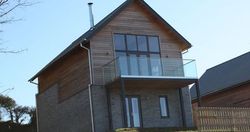 Modern two-story house with large windows and a glass balcony