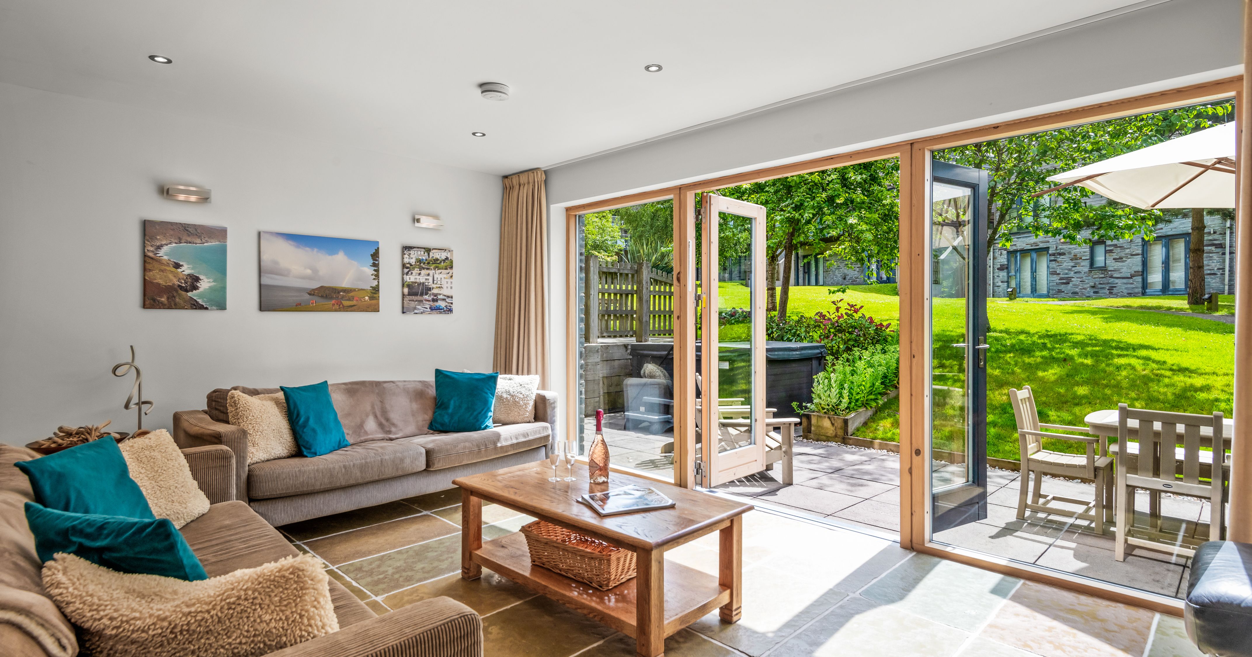 Modern living room with glass doors opening to a sunny patio and green garden.