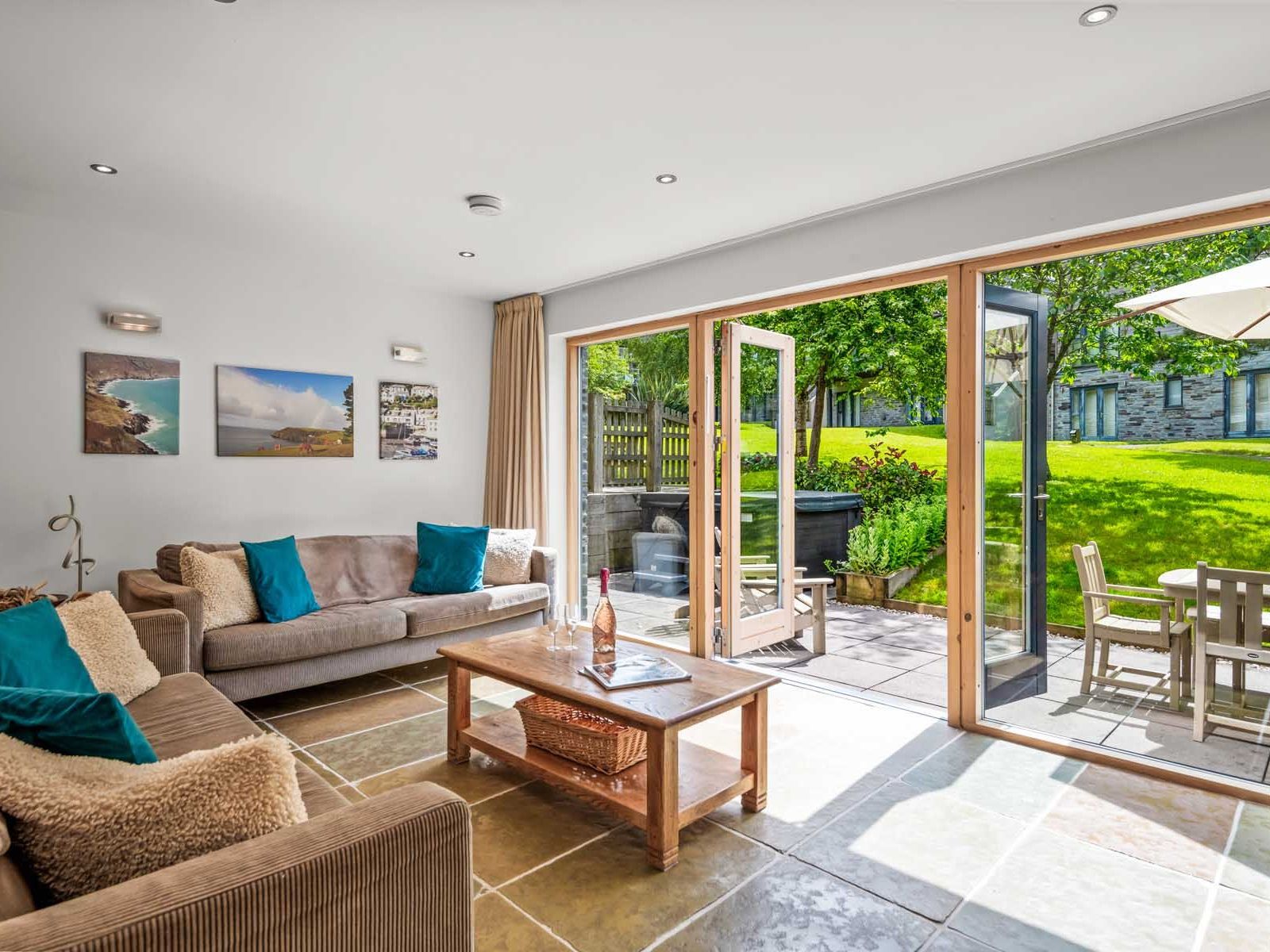 Bright living room with open glass doors leading to a sunny patio and green lawn outside.