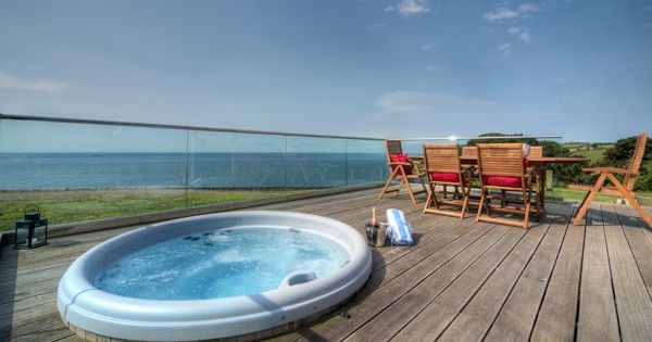 Outdoor deck with hot tub and dining area overlooking the ocean