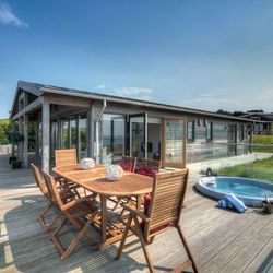 Modern wooden house with large deck, outdoor dining table and hot tub