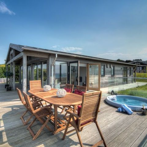 Modern wooden house with large deck, outdoor dining table and hot tub