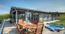 Modern wooden house with large deck, outdoor dining table and hot tub