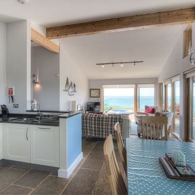 Open-plan kitchen, dining, and living space with large windows overlooking the sea.