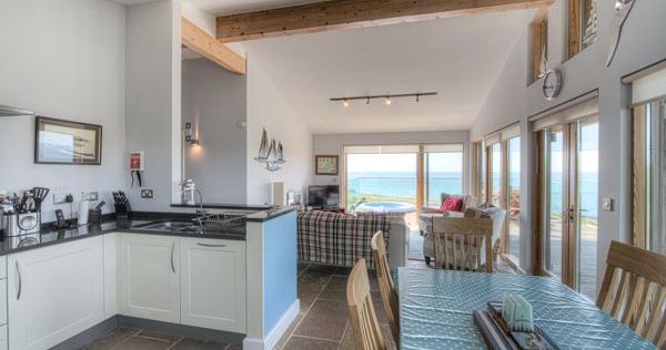 Open-plan kitchen, dining, and living space with large windows overlooking the sea.