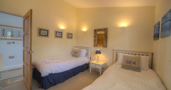 Cozy twin bedroom with two single beds, nautical-themed decor, and soft lighting.