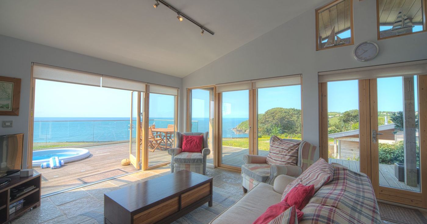 Modern living room with large windows overlooking the ocean and outdoor patio.