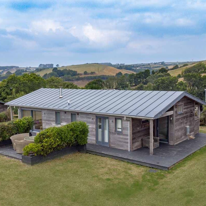 Modern wooden cabin with metal roof in a rural landscape