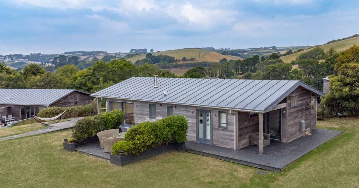 Modern wooden cabin with metal roof in a rural landscape