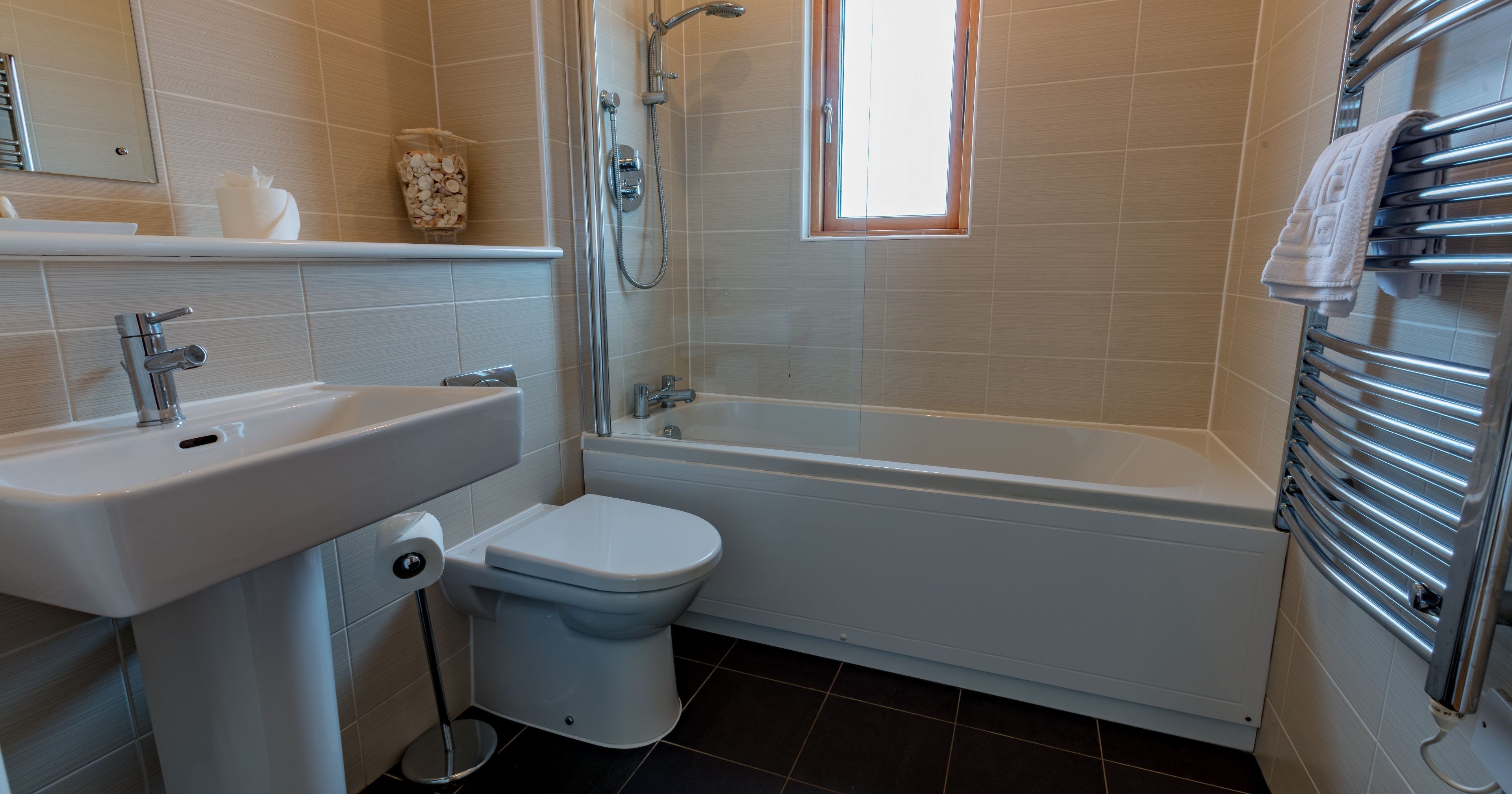 Modern bathroom with bathtub, sink, toilet, and heated towel rack