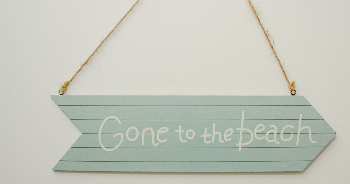 Wooden arrow sign hanging on a string that reads 'Gone to the beach'