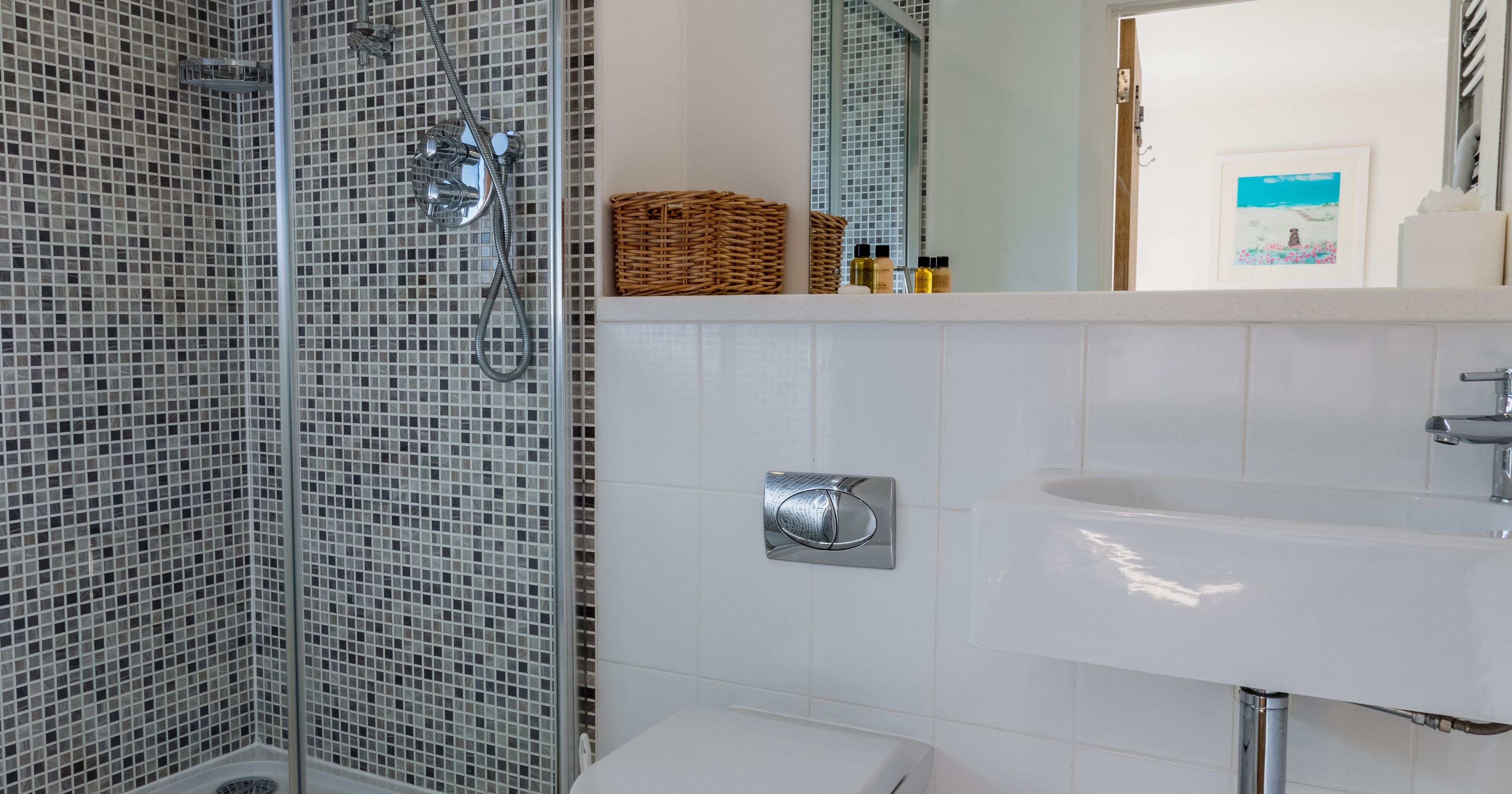 Modern bathroom with glass shower enclosure, toilet, and wall-mounted sink