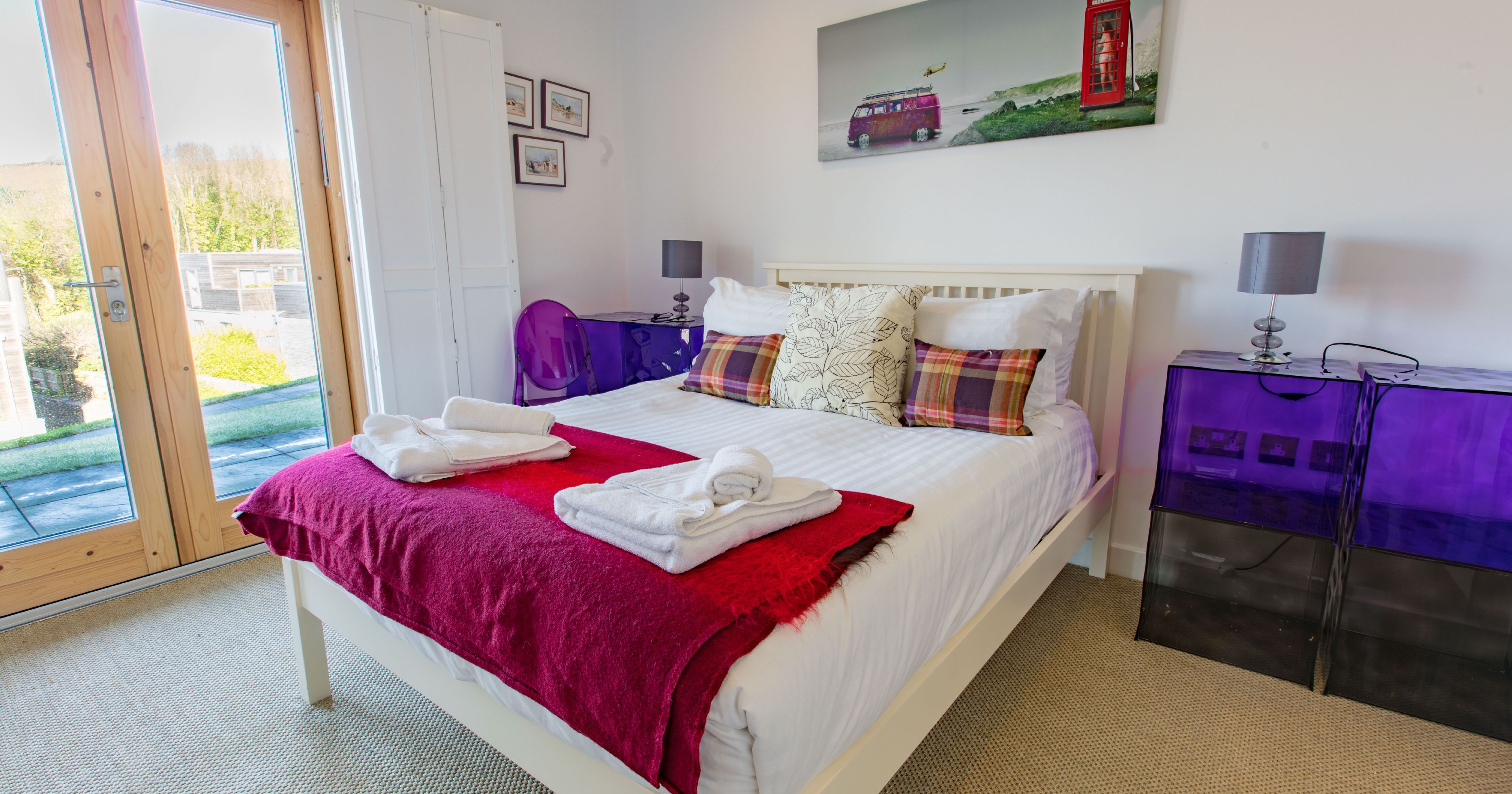 Modern bedroom with double bed, glass doors, and colorful decor