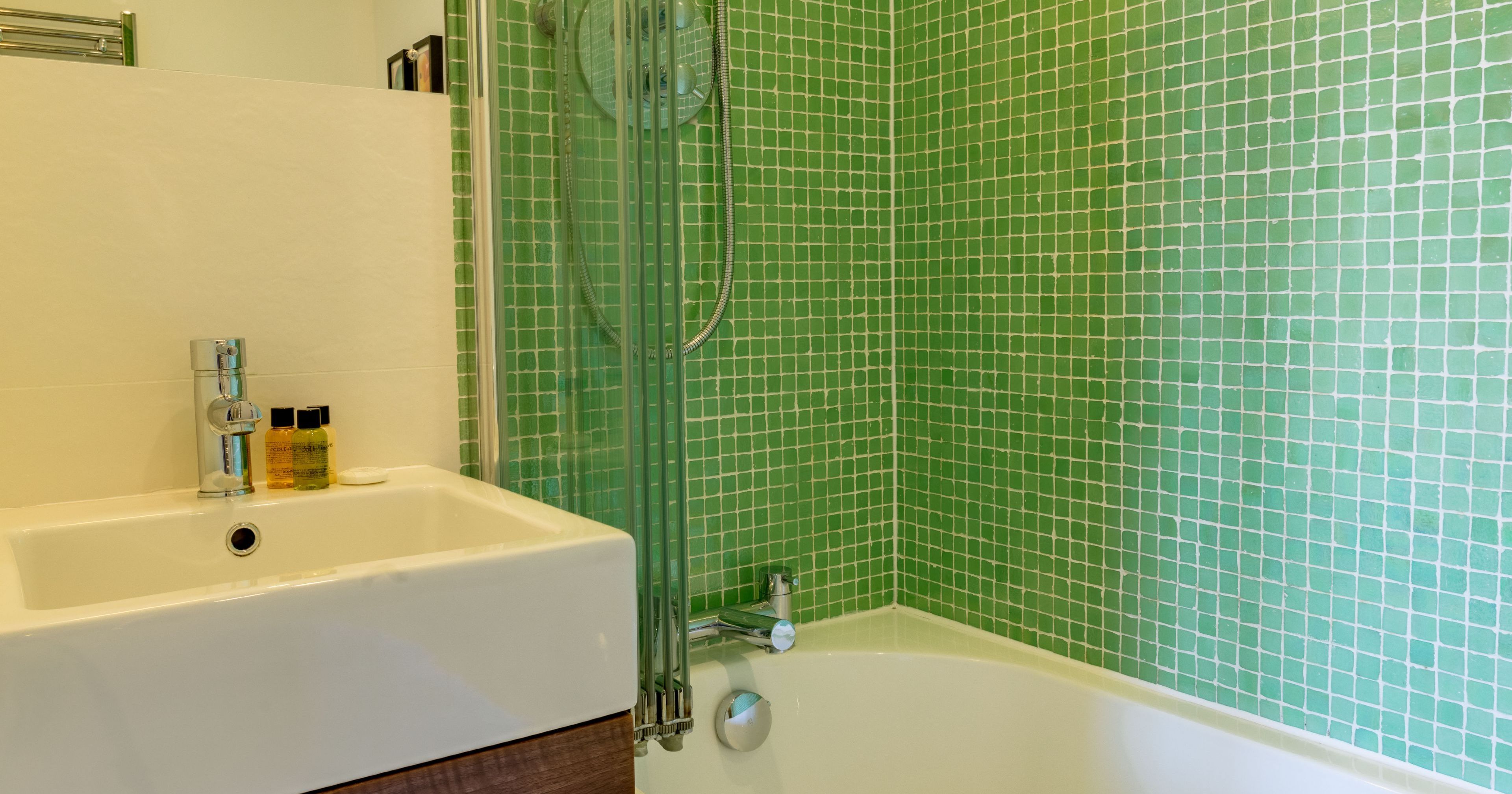 Modern bathroom with green tiled wall, bathtub, and sink