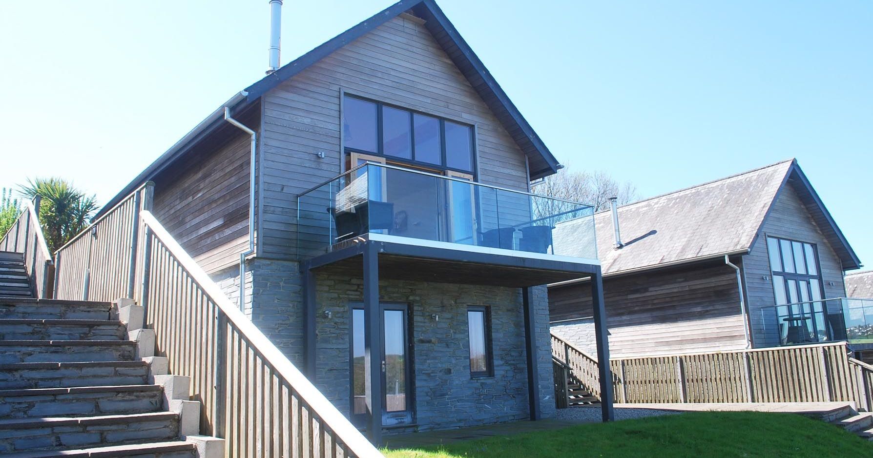 Modern wooden house with glass balcony and stone stairs