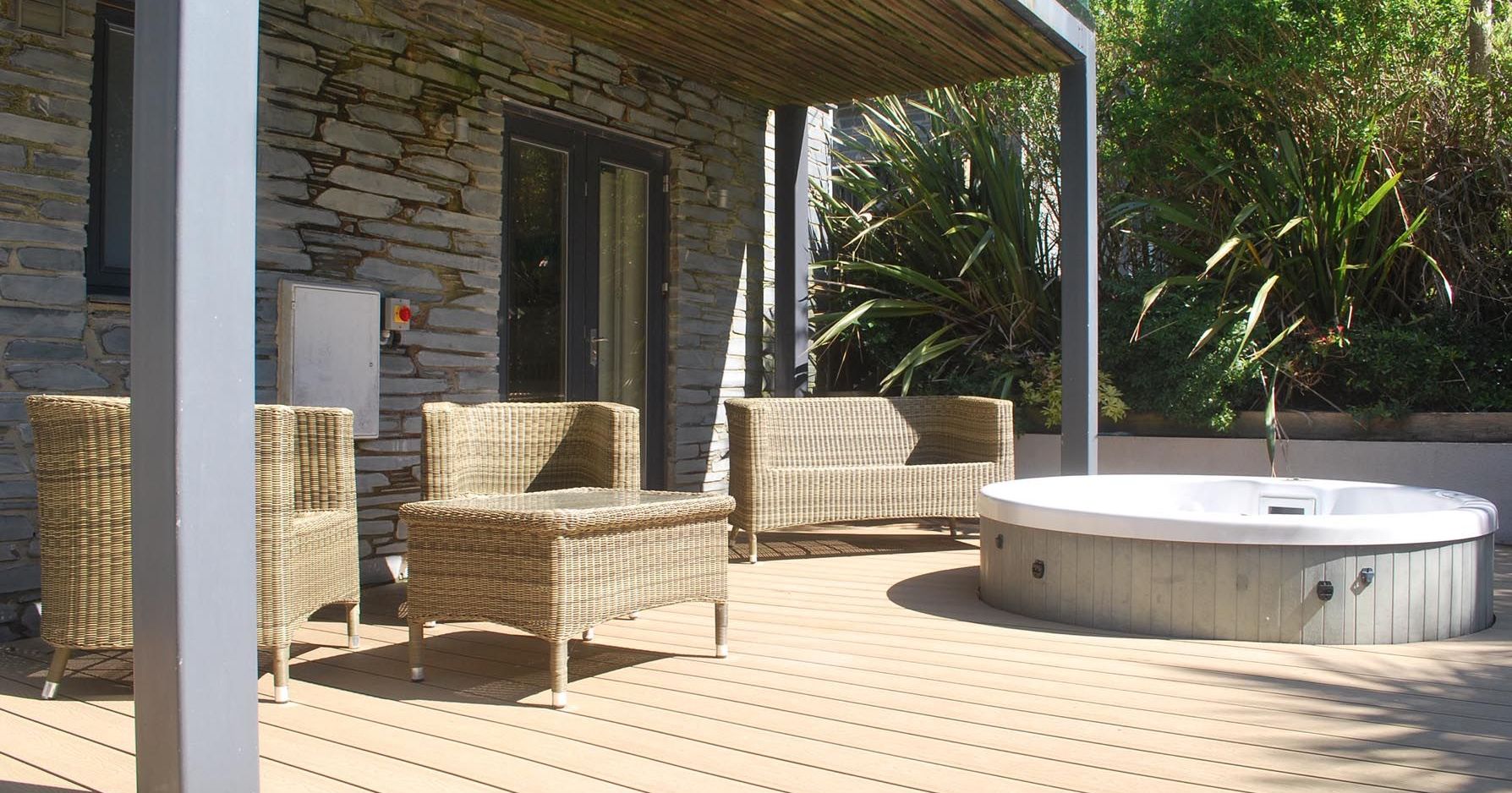 Outdoor patio with wicker furniture and a hot tub