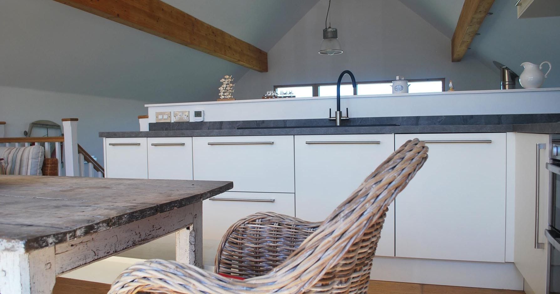 Modern loft kitchen with a rustic dining table and wicker chair