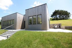 Modern house with wooden exterior and large windows surrounded by green grass