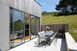 Modern outdoor patio with dining table set, barbecue, and sliding glass doors