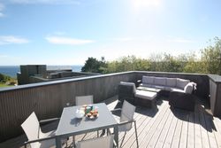 Modern rooftop terrace with outdoor furniture and ocean view
