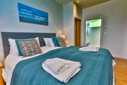 Modern bedroom with teal bedding, pillows, and towels arranged on the bed.