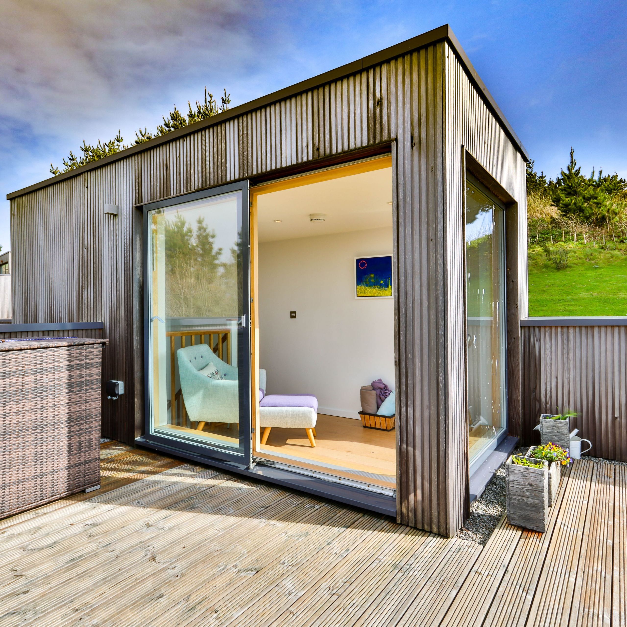 Modern wooden garden room with large sliding glass doors and deck